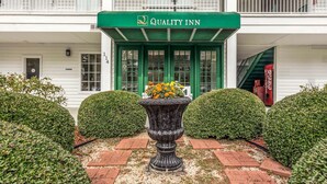 A building with a green awning labeled "Quality Inn" and a large decorative planter with flowers in front. - Quality Inn Lancaster (Lancaster)