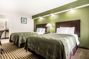 Two single beds with matching bedspreads and pillows, a desk with a chair, and a lamp.