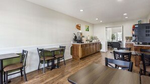 A dining area with wooden tables and chairs, a kitchen counter, and a refrigerator. - Quality Inn Lancaster (Lancaster)