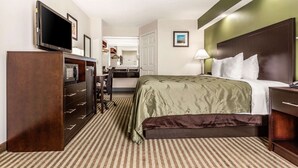 A hotel room with a bed, a desk, a dresser, a television, and a mirror. - Quality Inn Lancaster (Lancaster)