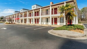 A multi-story motel with a central courtyard, a parking lot, and a palm tree.