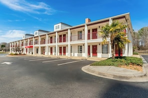 A multi-story motel with a central courtyard, a parking lot, and a palm tree. - Red Roof Inn & Suites Wilson (Wilson)