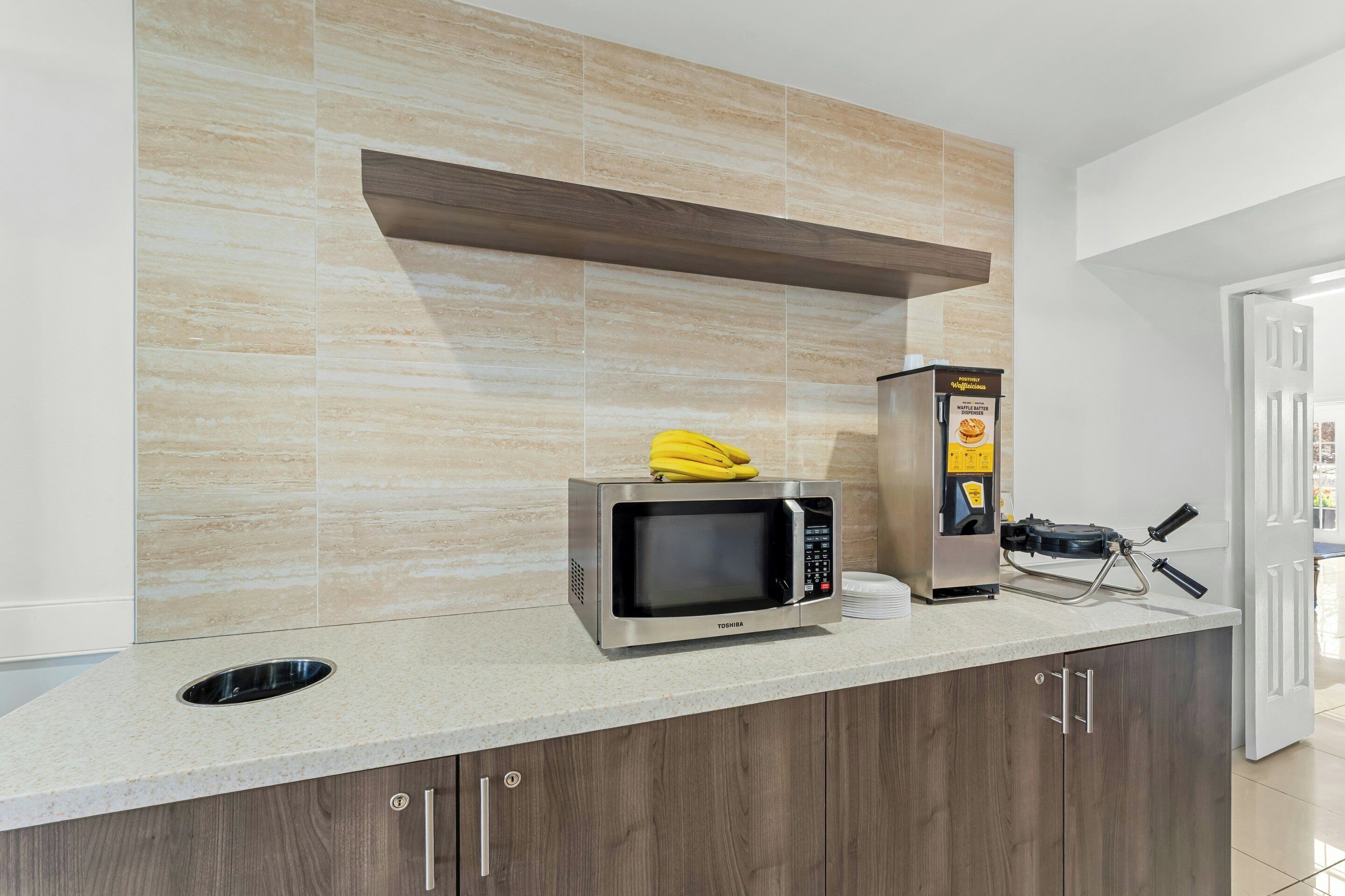 Una cocina con microondas, tostadora y una banana sobre la encimera.