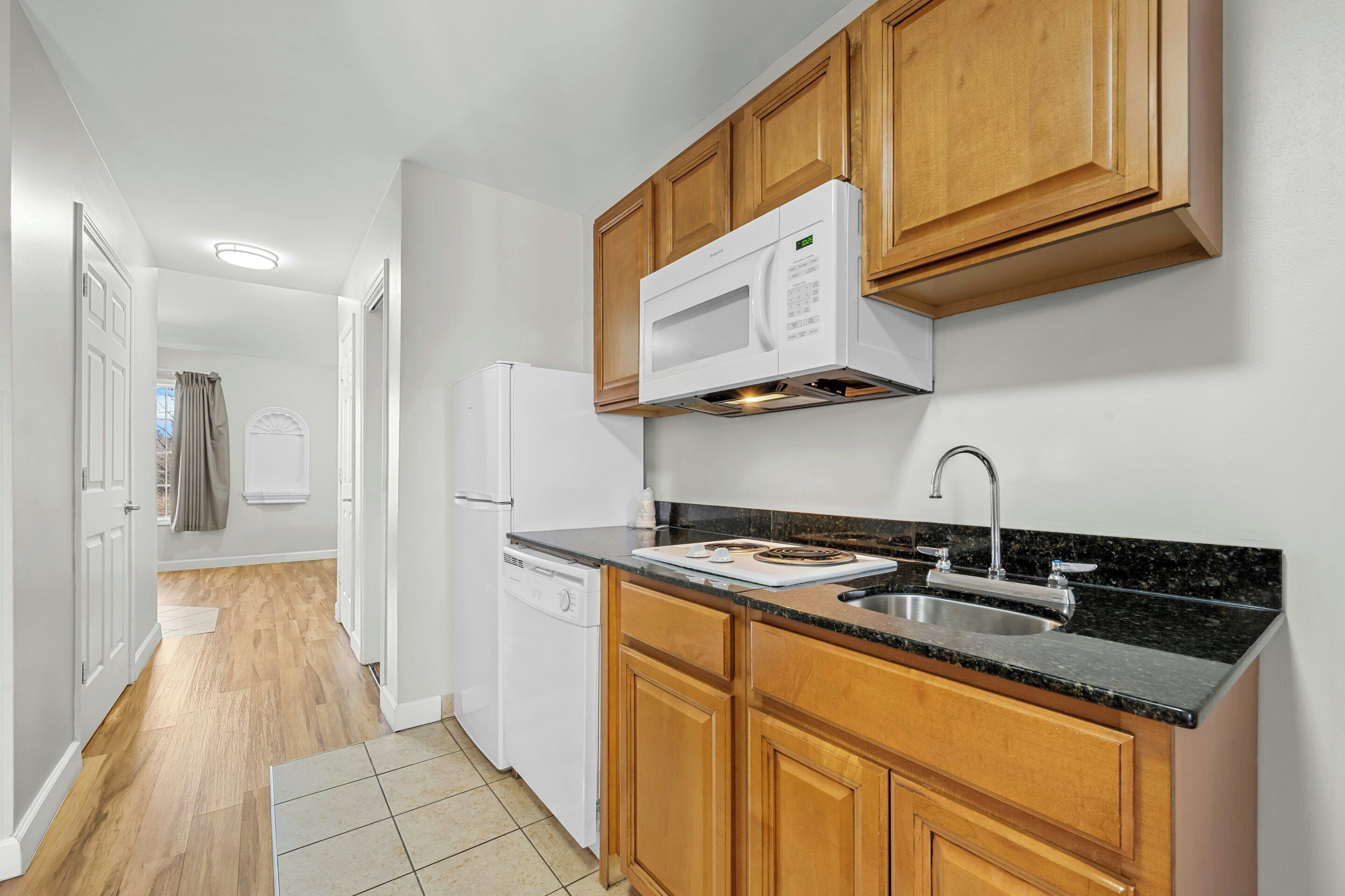 A kitchen with wooden cabinets, a microwave, a sink, and a dishwasher.