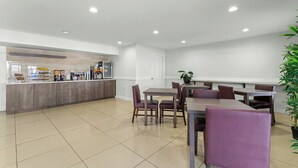 A modern dining area with a counter, chairs, and a potted plant.