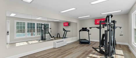 A gym with exercise equipment, a large mirror, and a view of a swimming pool.