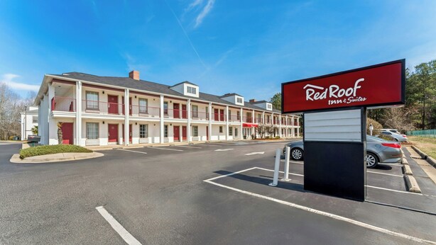 A Red Roof Inn & Suites with a two-story building, parking lot, and a clear sky.