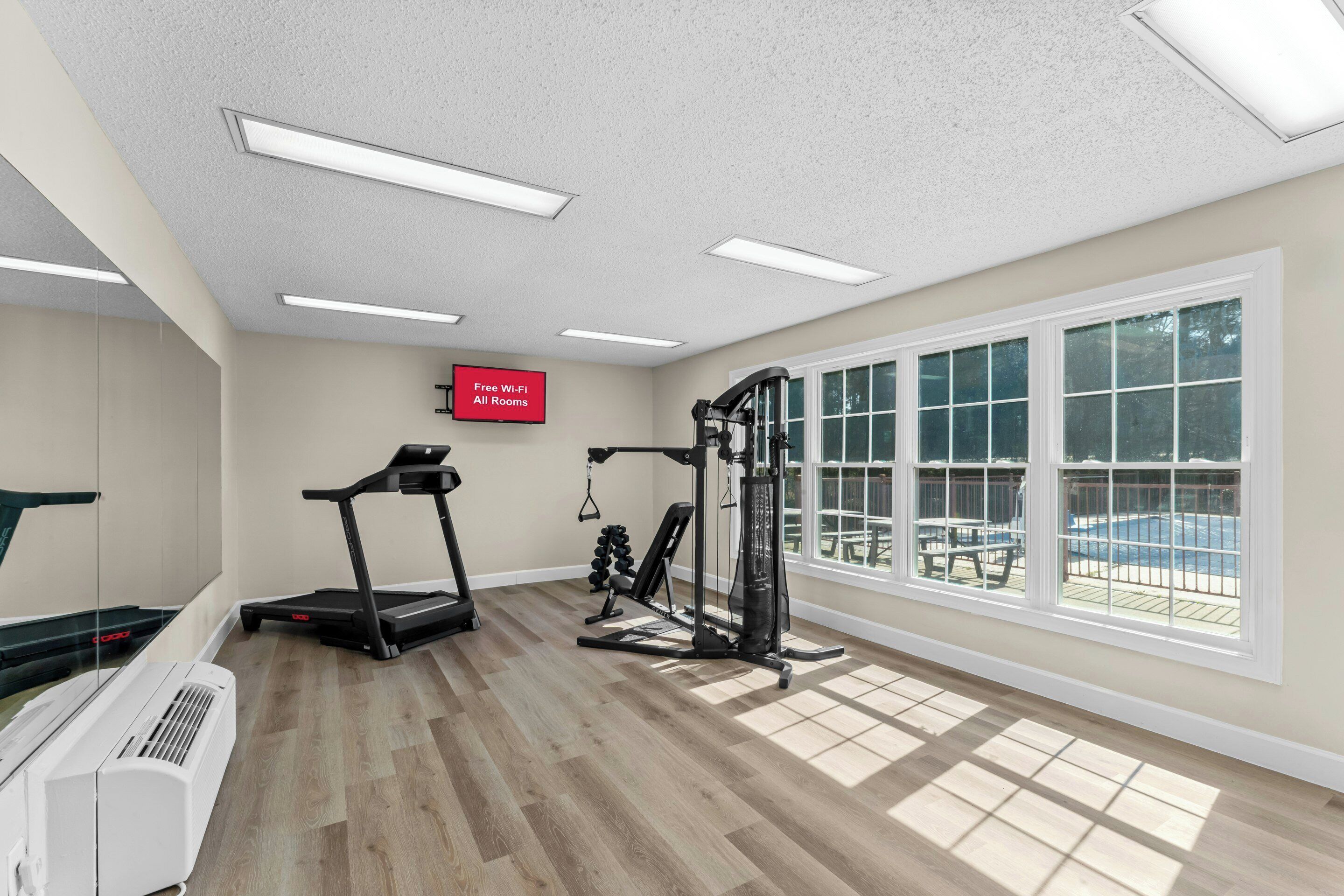 A gym with exercise equipment, a treadmill, and a sign indicating free Wi-Fi in all rooms.