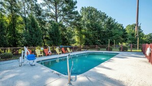 A swimming pool with a metal ladder, surrounded by a fence and trees. - Red Roof Inn & Suites Wilson (Wilson)