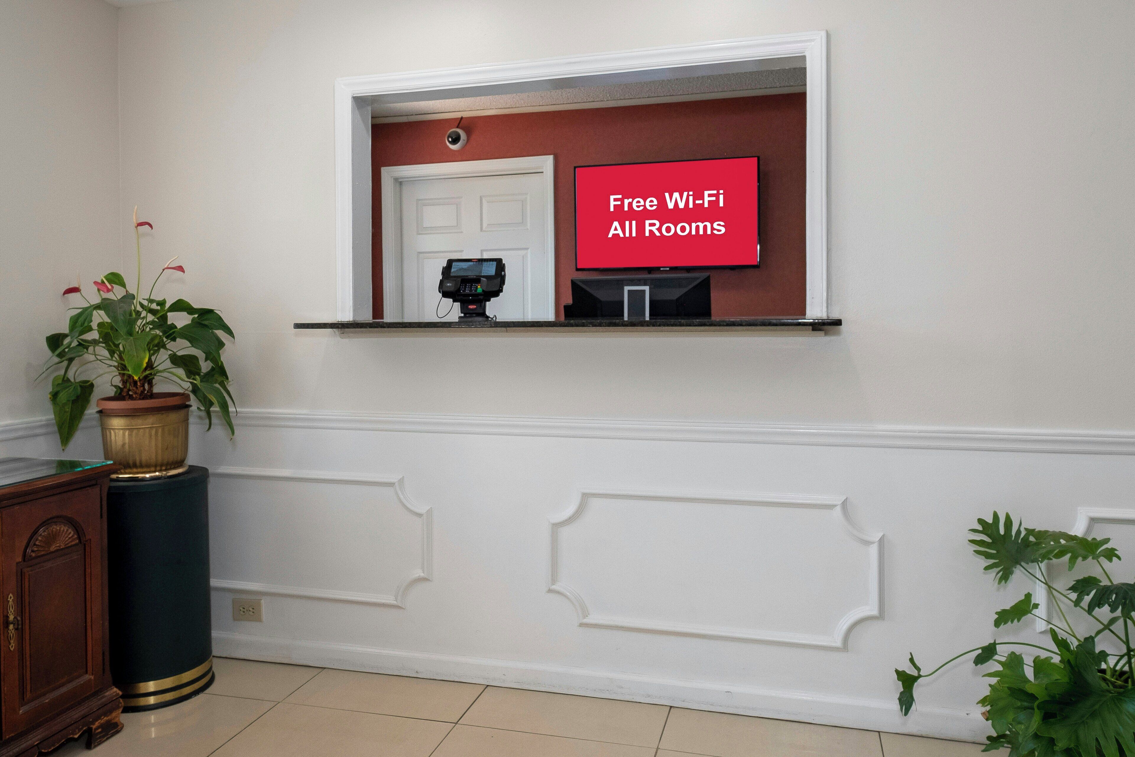 A room with a white wall, a door, a mounted television, and a potted plant.