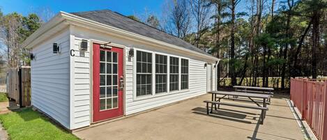 A small building with a red door, large windows, and a picnic table area.