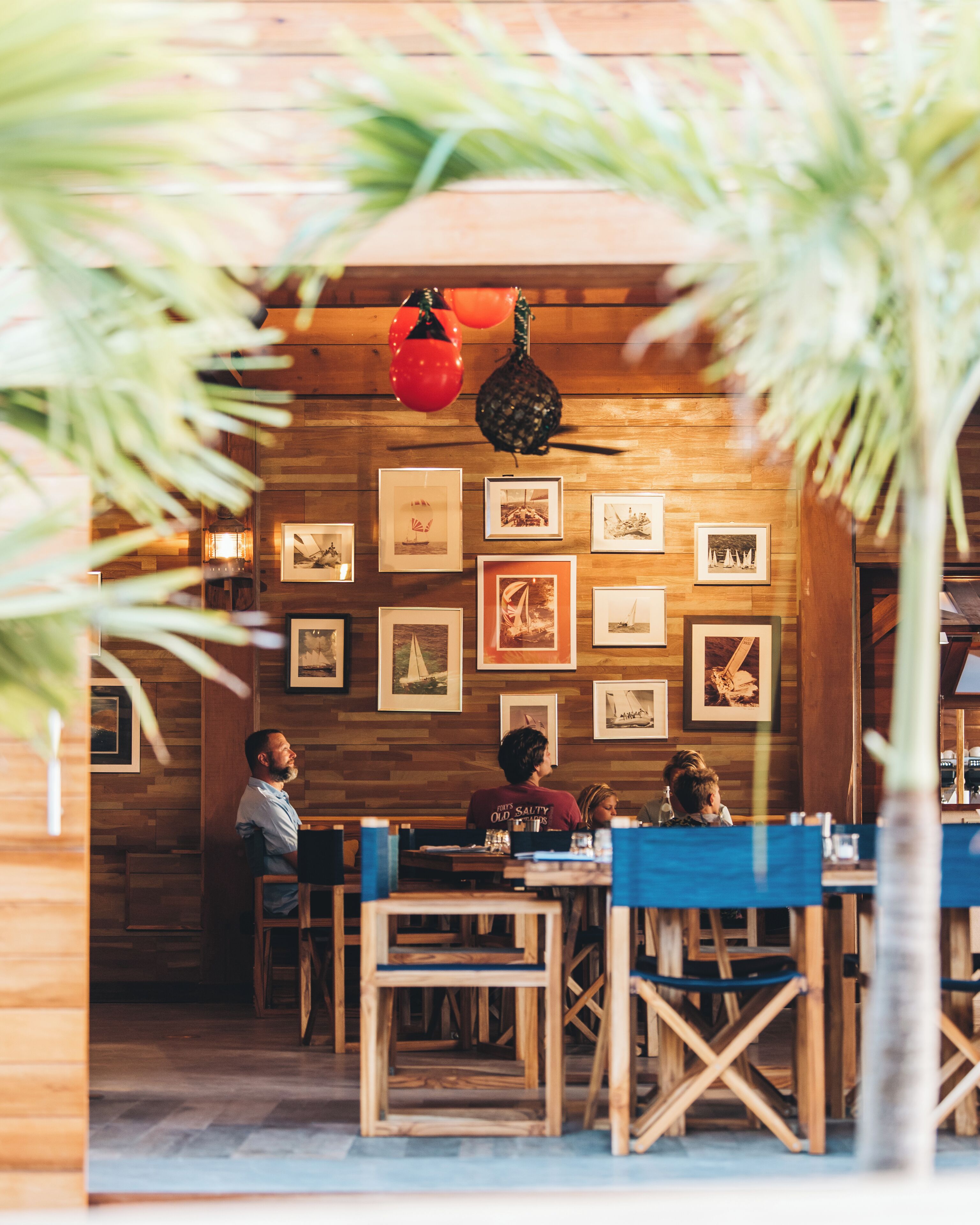 A restaurant with wooden walls and framed pictures. There are tables and chairs for dining.