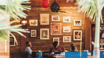 A restaurant with wooden walls and framed pictures. There are tables and chairs for dining.