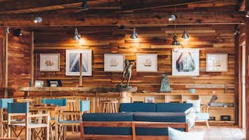 A wooden interior with a bar area, seating, and framed artwork on the walls.