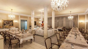 Un comedor elegante con varias mesas, sillas y candelabros.