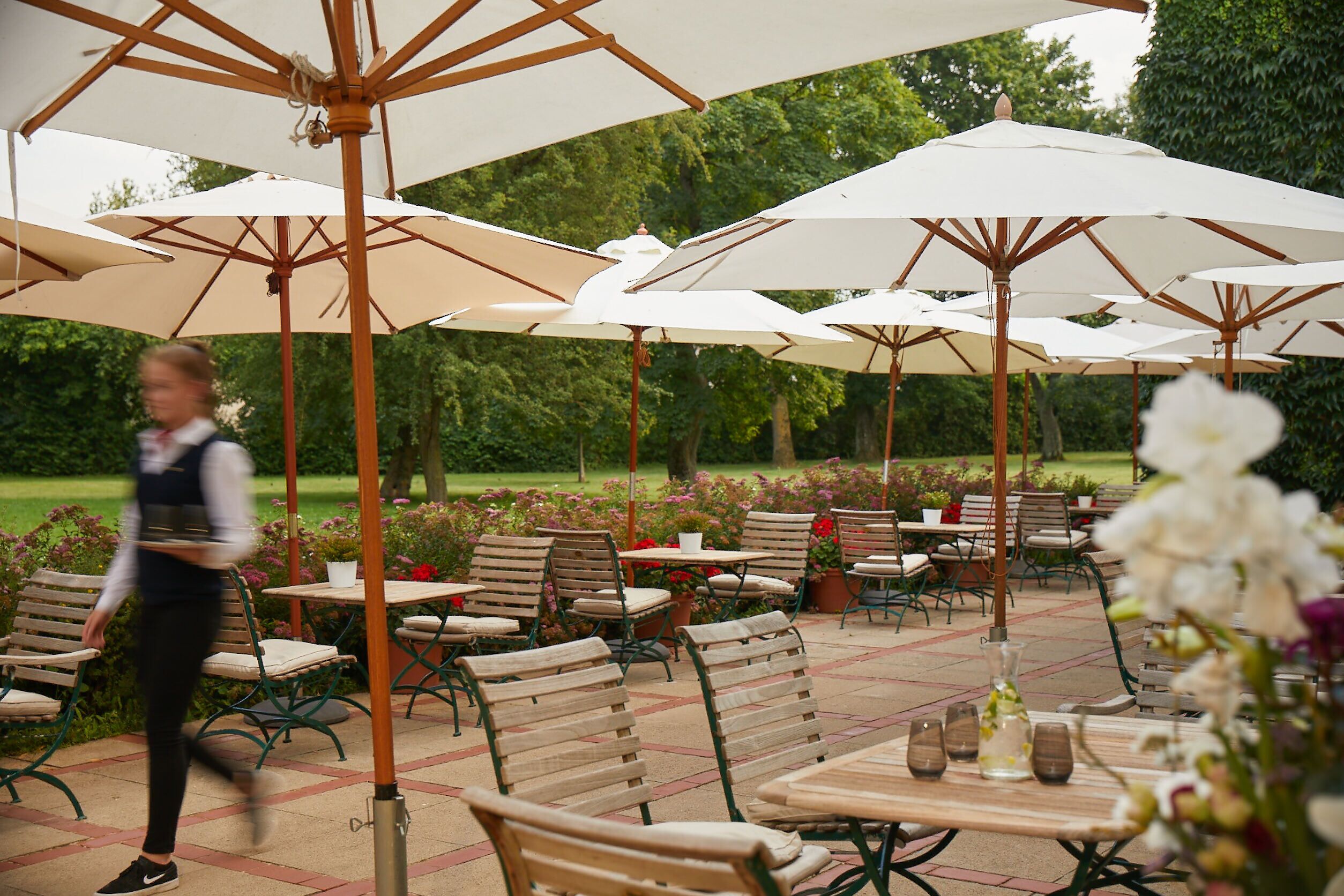 An outdoor patio with multiple tables and chairs, surrounded by large white umbrellas.