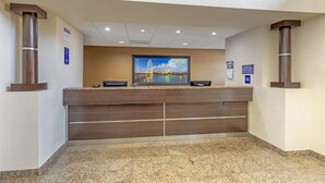 A reception area with a marble floor, wooden reception desk, and a large framed picture of a cityscape. - Best Western Northwest Inn (Dallas)
