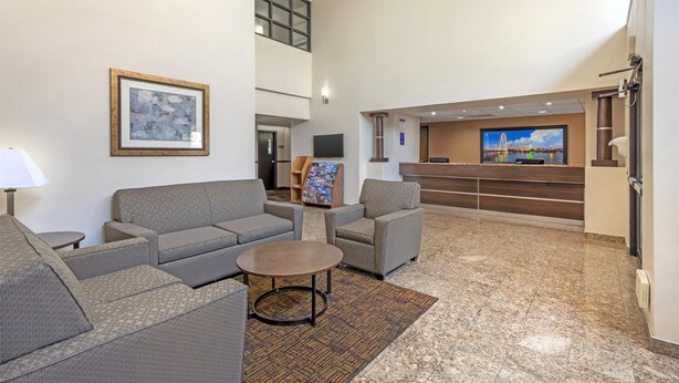 A spacious lobby with a reception desk, seating area with sofas and a coffee table, and a large framed artwork on the wall. - Best Western Northwest Inn (Dallas)