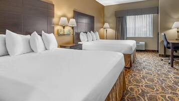A hotel room with two beds, a desk, and a window with curtains.