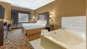 A hotel room with a large bed, a bathroom with a bathtub, a desk, and a chair. - Best Western Northwest Inn (Dallas)