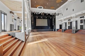 A spacious indoor area with a wooden floor, a stage with lighting equipment, and a large screen. - Best Western Torvehallerne (Vejle)