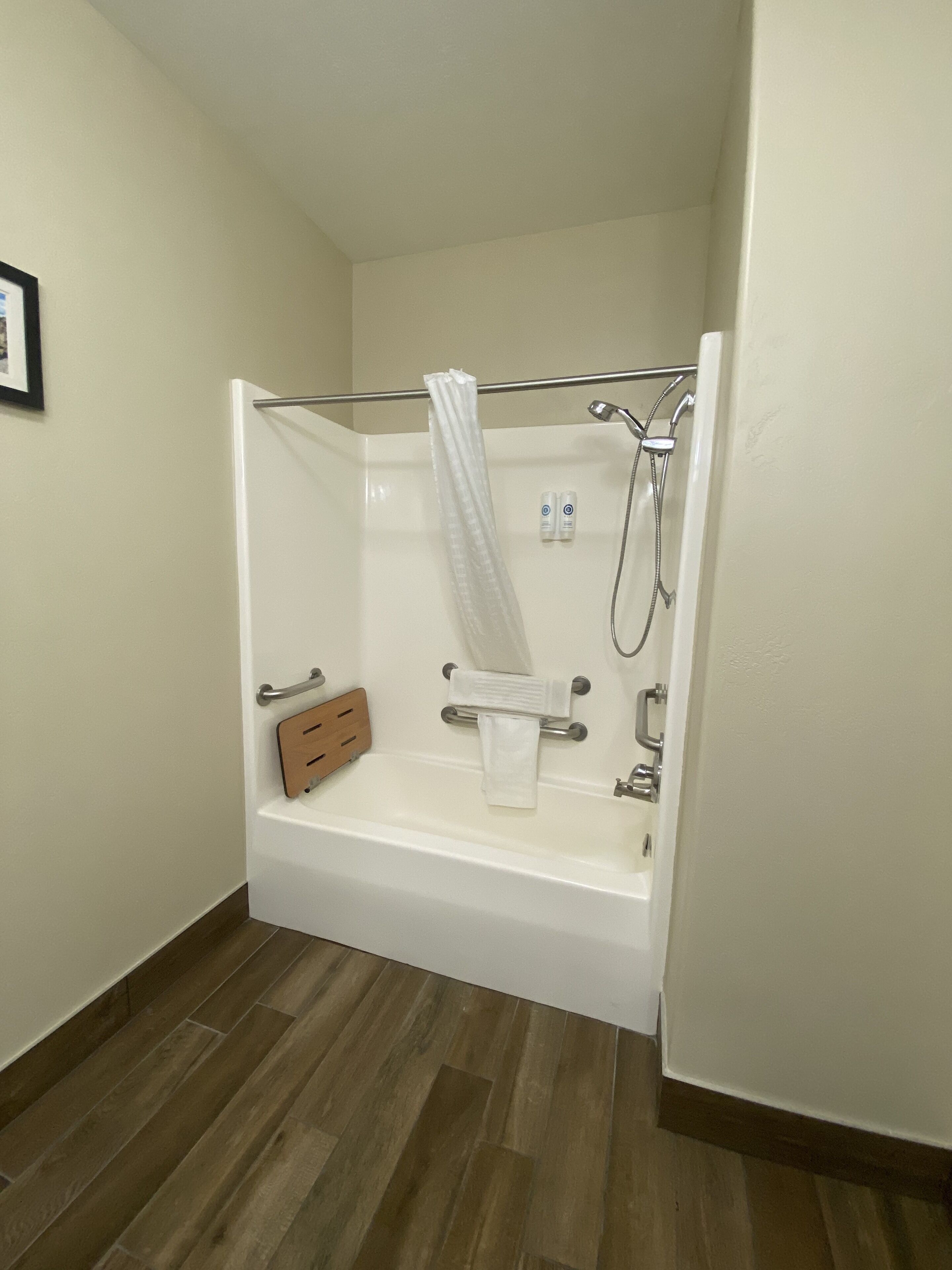 Une salle de bain avec une douche, une baignoire et une étagère en bois.