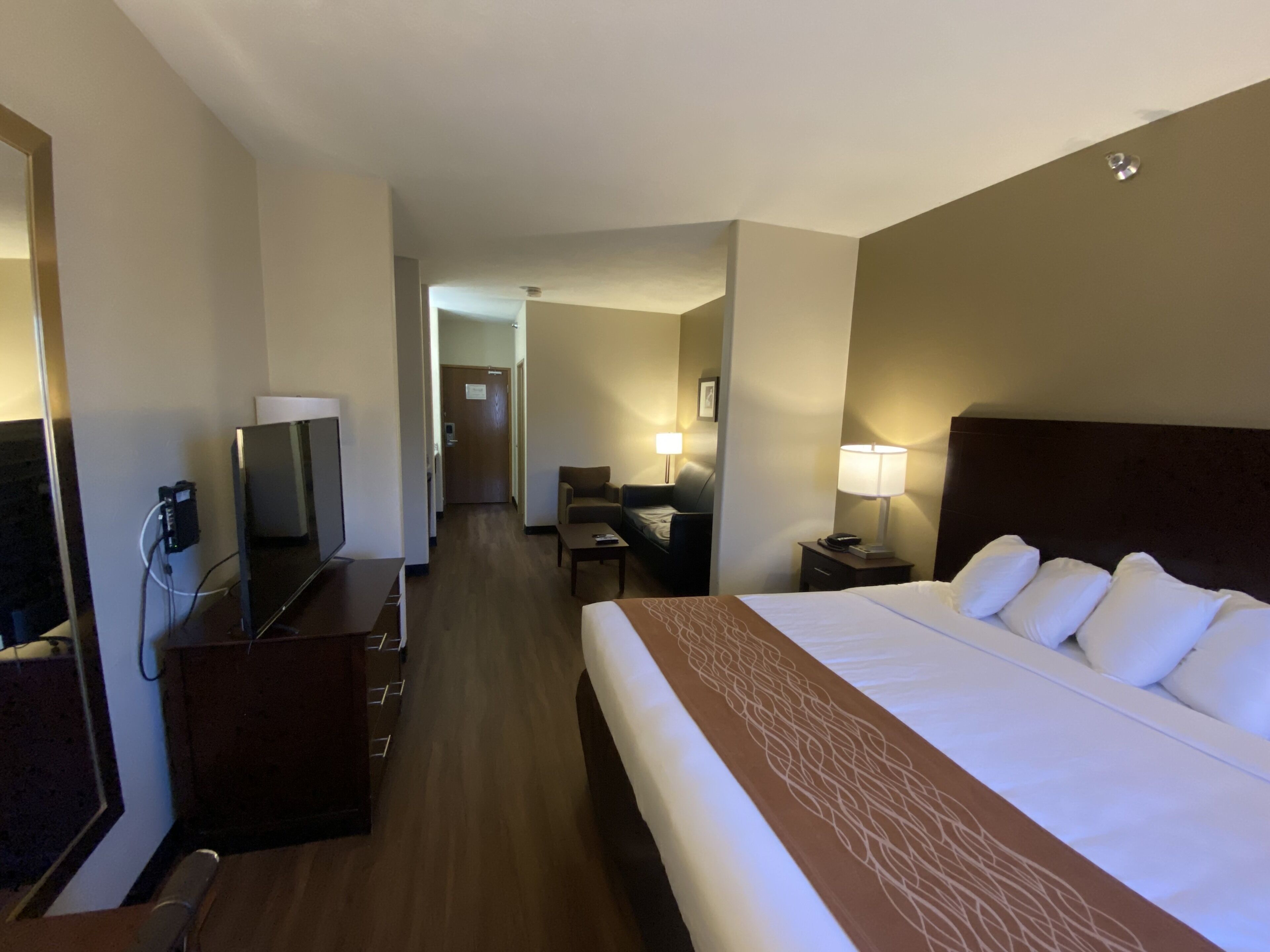 Habitació d'hotel amb un llit gran, una taula de treball, una cadira, una televisió i una làmpada.