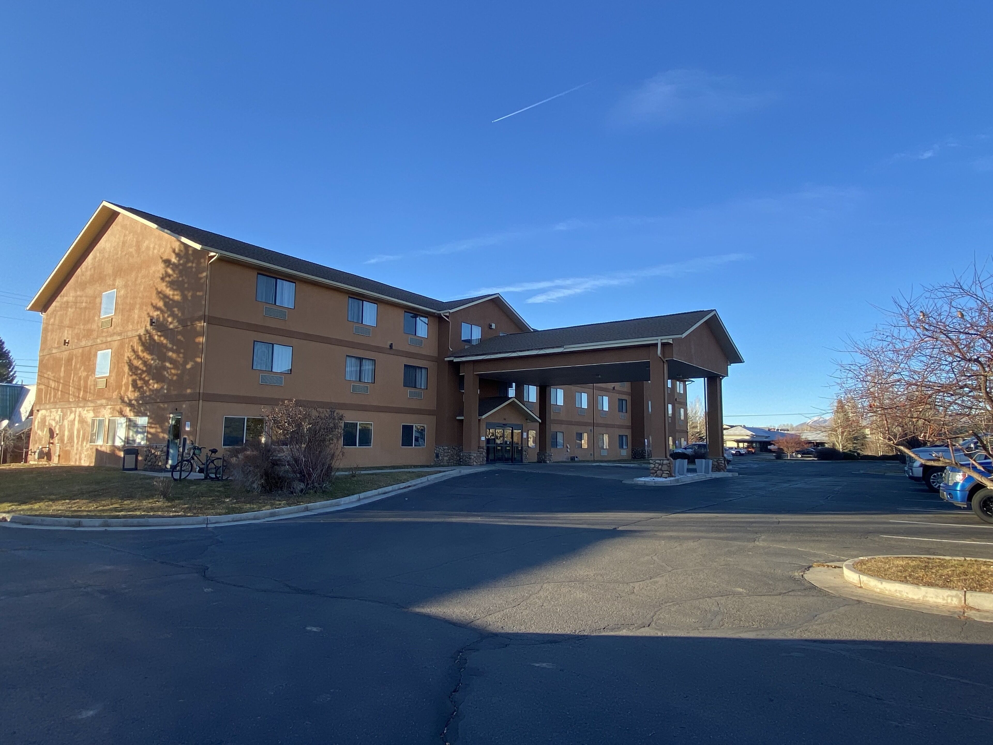 A multi-story hotel with a covered entrance and a parking lot.