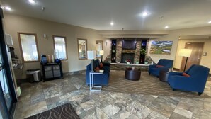 Een ruime lobby met een open haard, comfortabele zitplaatsen en een schoon, modern design.
