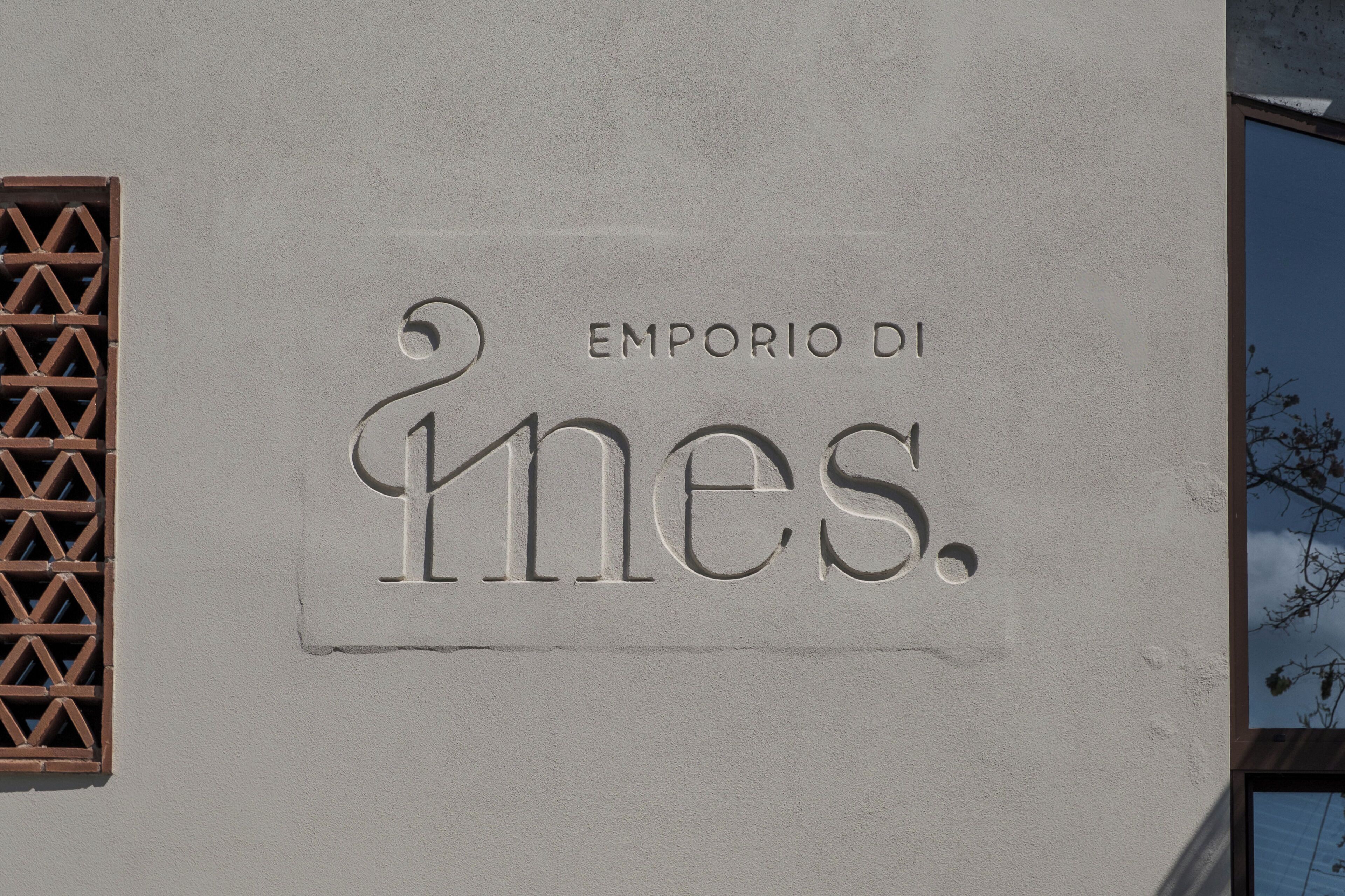 Eine Gebäudefassade mit der Aufschrift "EMPORIO DI" und dem Namen "Mies" in großen, geprägten Buchstaben.