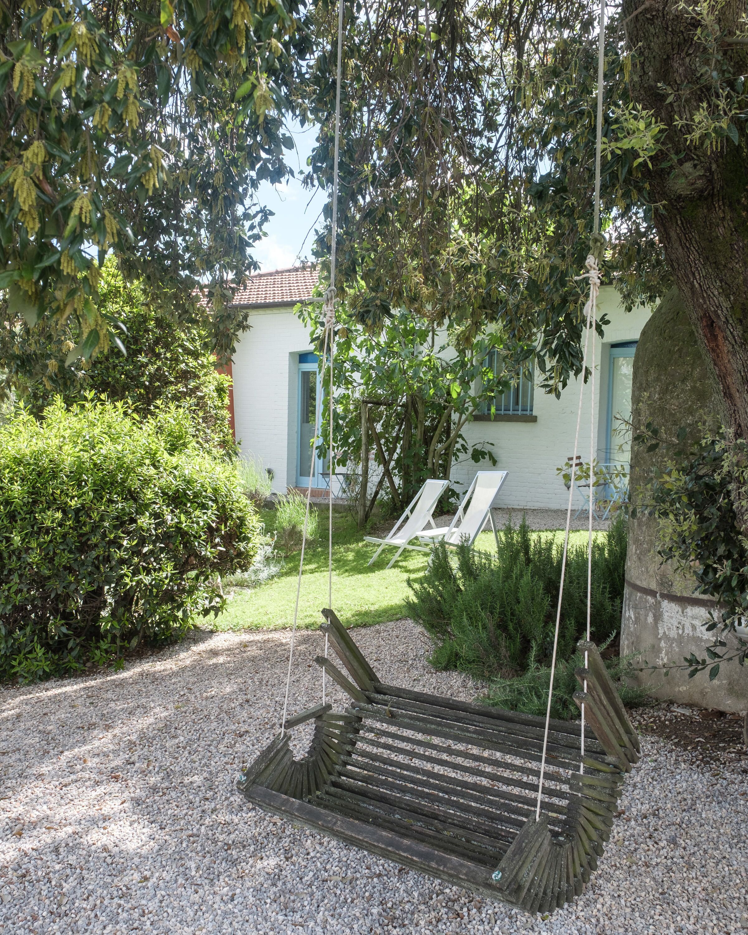 A wooden swing set in a garden with a white building in the background.
