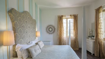 A bedroom with a large bed, a bedside table with a lamp, a dresser, and a mirror.