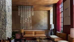 Ein modernes Wohnzimmer mit Sofa, Couchtisch und Sesseln, einer Pendelleuchte und einem großen Fenster.
