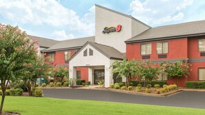 A hotel with a red and white exterior, a 'Super 8' sign, and a well-maintained front lawn with flowering bushes.