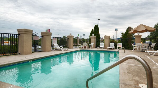 Relax by the pool surrounded by lounge chairs and shaded seating areas.