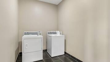 A laundry room with two front-loading washing machines and a dryer.