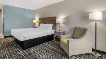 A hotel room with a bed, a chair, a nightstand, and two lamps.