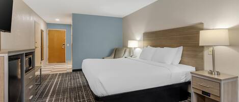 Una habitación de hotel con cama, lámparas de noche, escritorio y televisión.