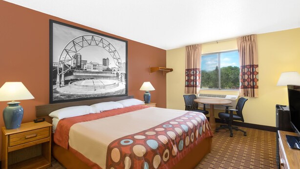 A hotel room with a large bed, two bedside tables with lamps, a desk with a chair, a TV, and a large window with curtains. - Super 8 by Wyndham Boone (Boone)