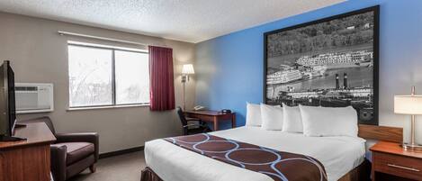 A hotel room with a large bed, a desk, a chair, a TV, a window with curtains, and a cityscape painting on the wall.