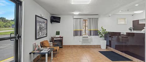 A hotel lobby with a reception desk, seating area, and a large window.