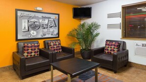 A lobby with two leather sofas, a coffee table, a framed picture of Dubuque, IOWA, a potted plant, and a television on the wall.