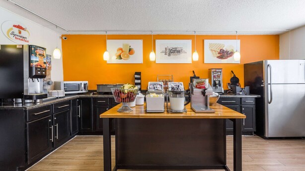 A modern kitchen with a central island, black cabinets, and orange walls.