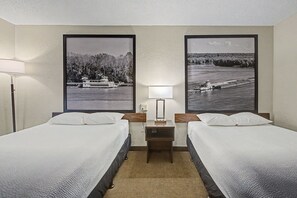 A hotel room with two beds, a nightstand with a lamp, and two large framed pictures of a river scene. - Super 8 by Wyndham Dubuque (Dubuque)