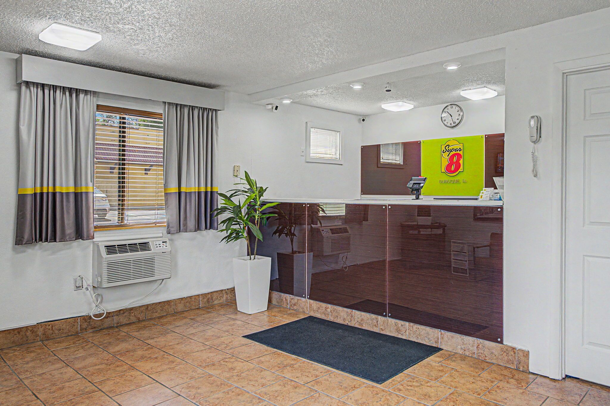 A reception area with a reception desk, a clock, a telephone, and a potted plant.