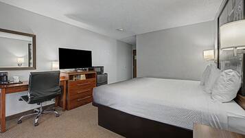 Une chambre d’hôtel comprenant un lit, un bureau avec une chaise, une télévision, une commode et une lampe.