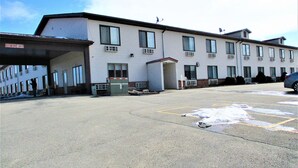 A building with multiple windows and a parking lot with snow on the ground. - Sunset Inn (Williamsburg)