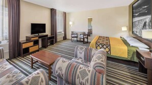 Een hotelkamer met een televisie, bank, bed en een eettafel.