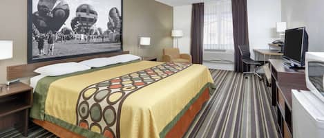 A hotel room with a large bed, a desk with a computer, a TV, and a large framed picture on the wall.