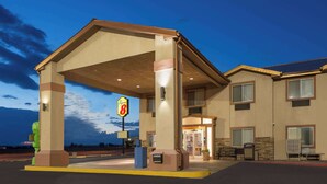 Een hotel met een overdekt buitengebied, een bord voor een restaurant en een tankstation.